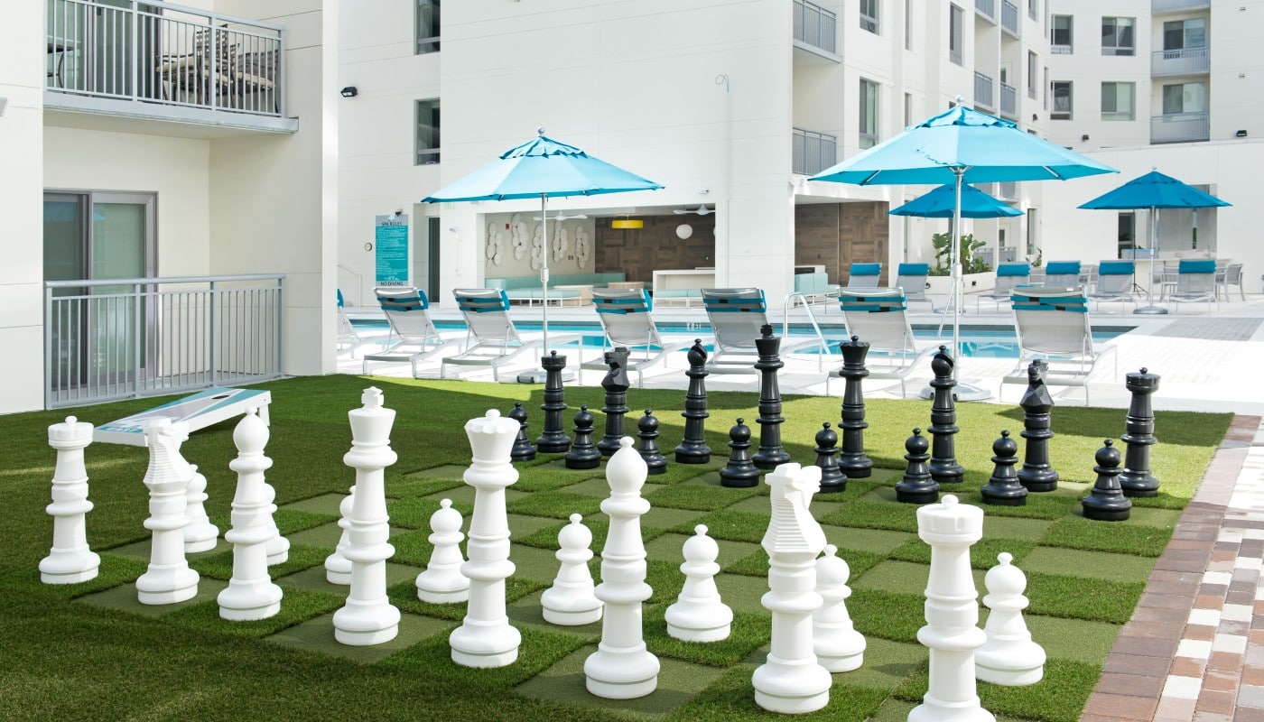 420 east large outdoor chess board with view of pool, chaise lounge chairs and umbrellas in the background - jefferson apartment group