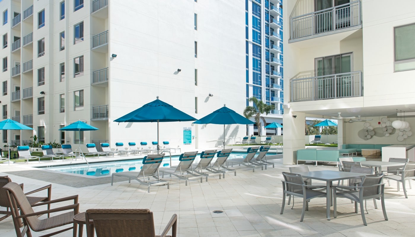 420 east outdoor lounge with pool, social seating, tables, chairs, and view of apartment building with balconies in the background - jefferson apartment group