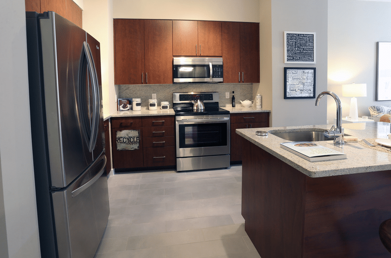 asher kitchen with stainless steel appliances, espresso cabinetry, granite countertops, modern artwork and view of living area - jefferson apartment group