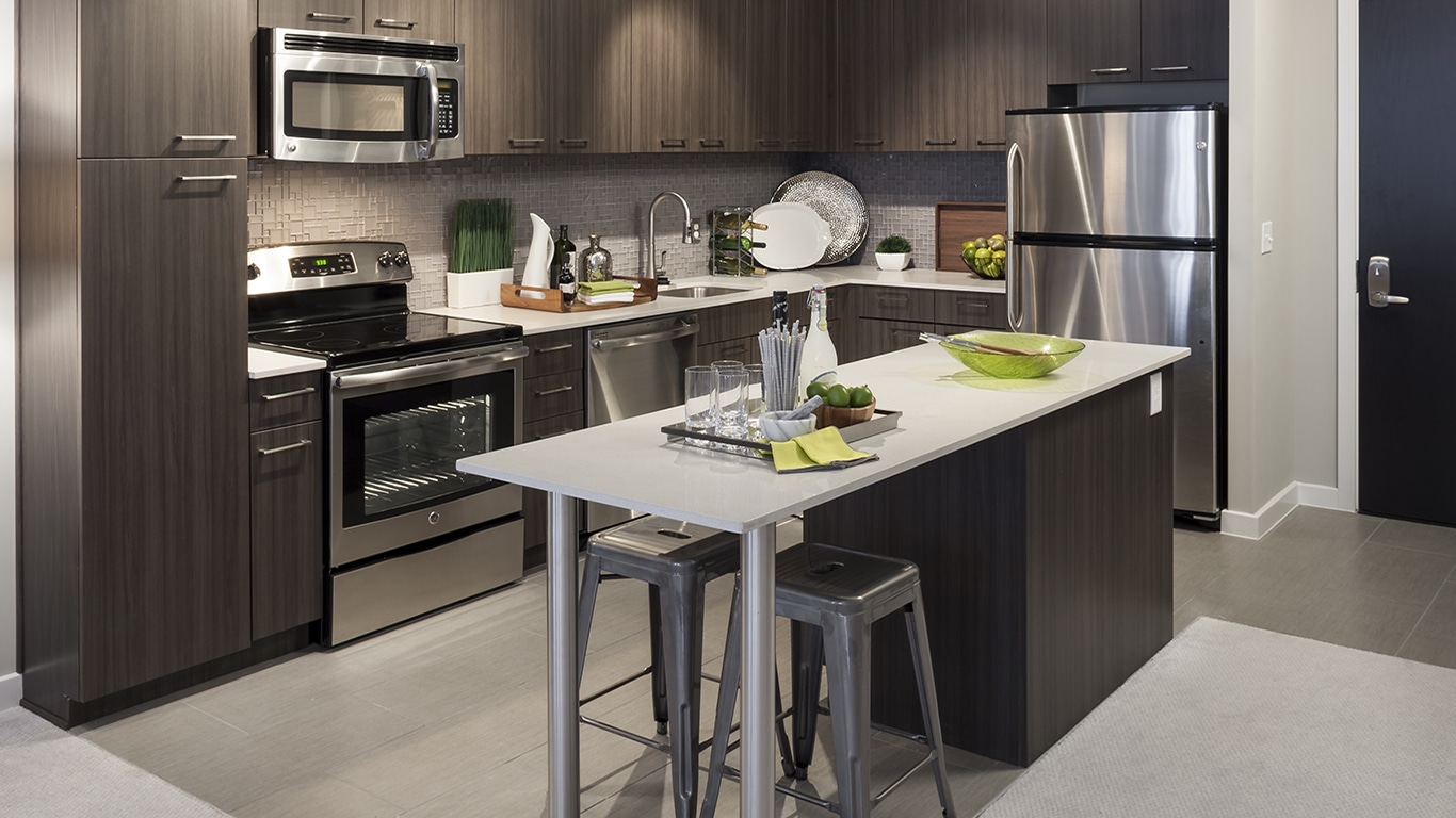 tellus kitchen with stainless steel appliances, tiled flooring, kitchen island, and quartz countertops - jefferson apartment group