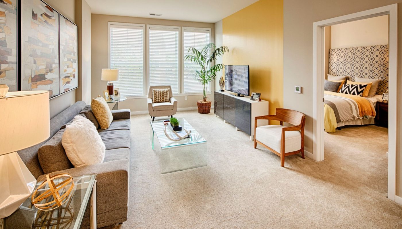 living space with sofa, coffee table, end table, chairs, oversized windows, tv, credenza and view of bedroom at Jefferson square luxury Baltimore apartments