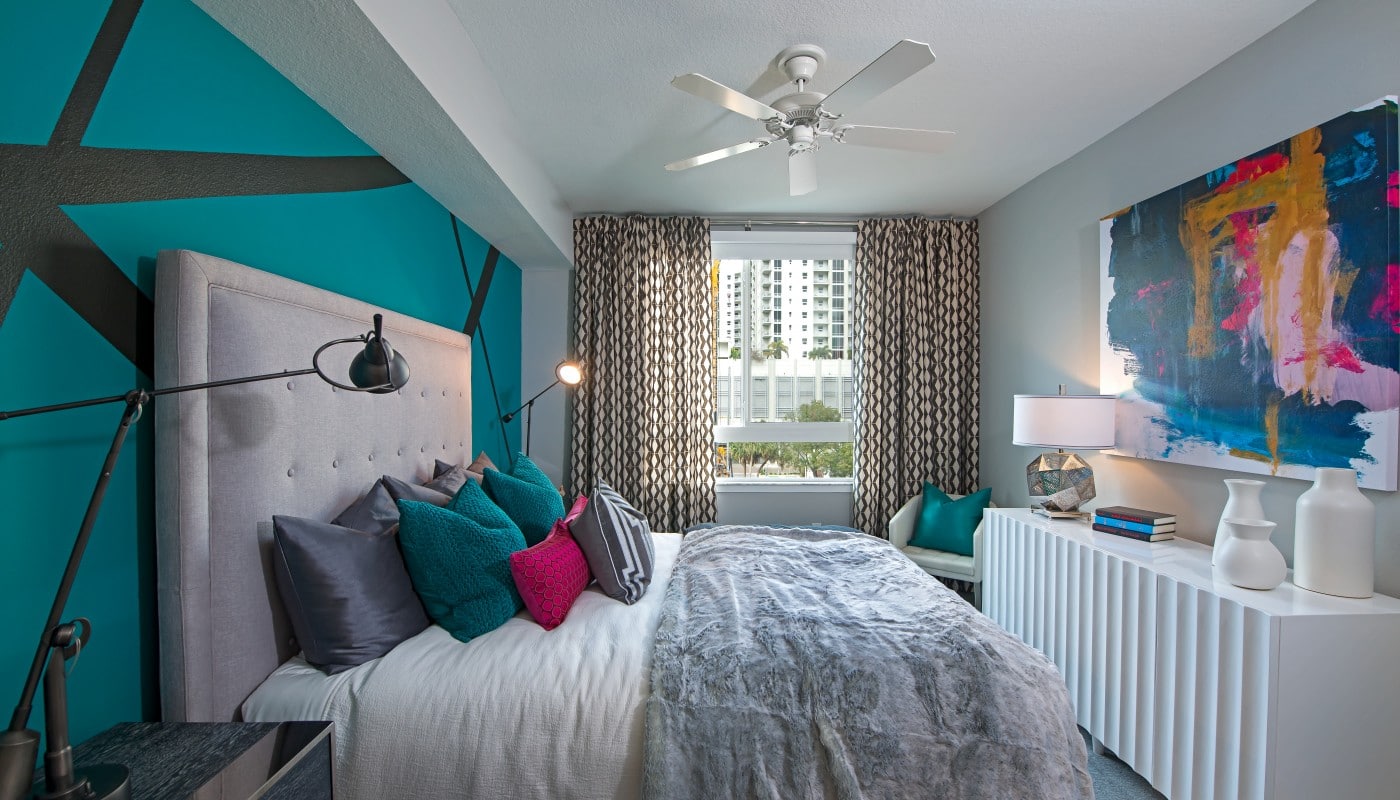 bedroom with bed, dresser, night stand, modern artwork, ceiling fan and large window - jefferson apartment group