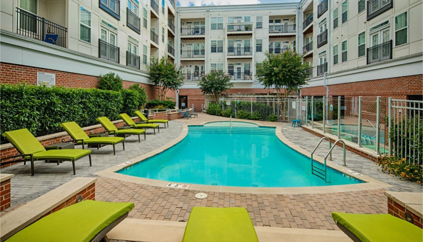 pool in courtyard with social seating, chaise lounge chairs, and view of balconies at jefferson square luxury baltimore apartments
