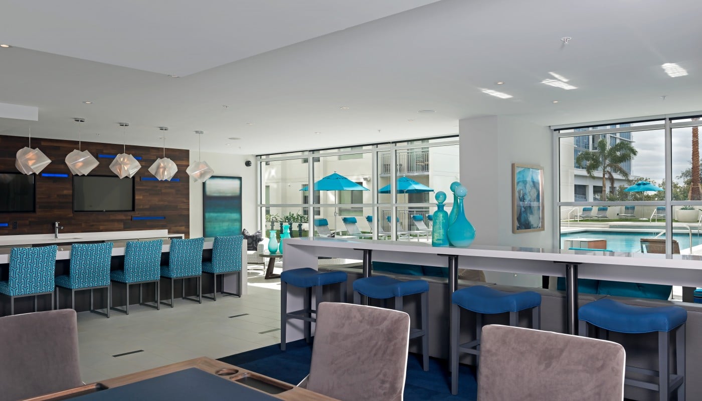 club house with bar seating, poker table, view of pool, large windows, modern artwork and modern lighting - jefferson apartment group