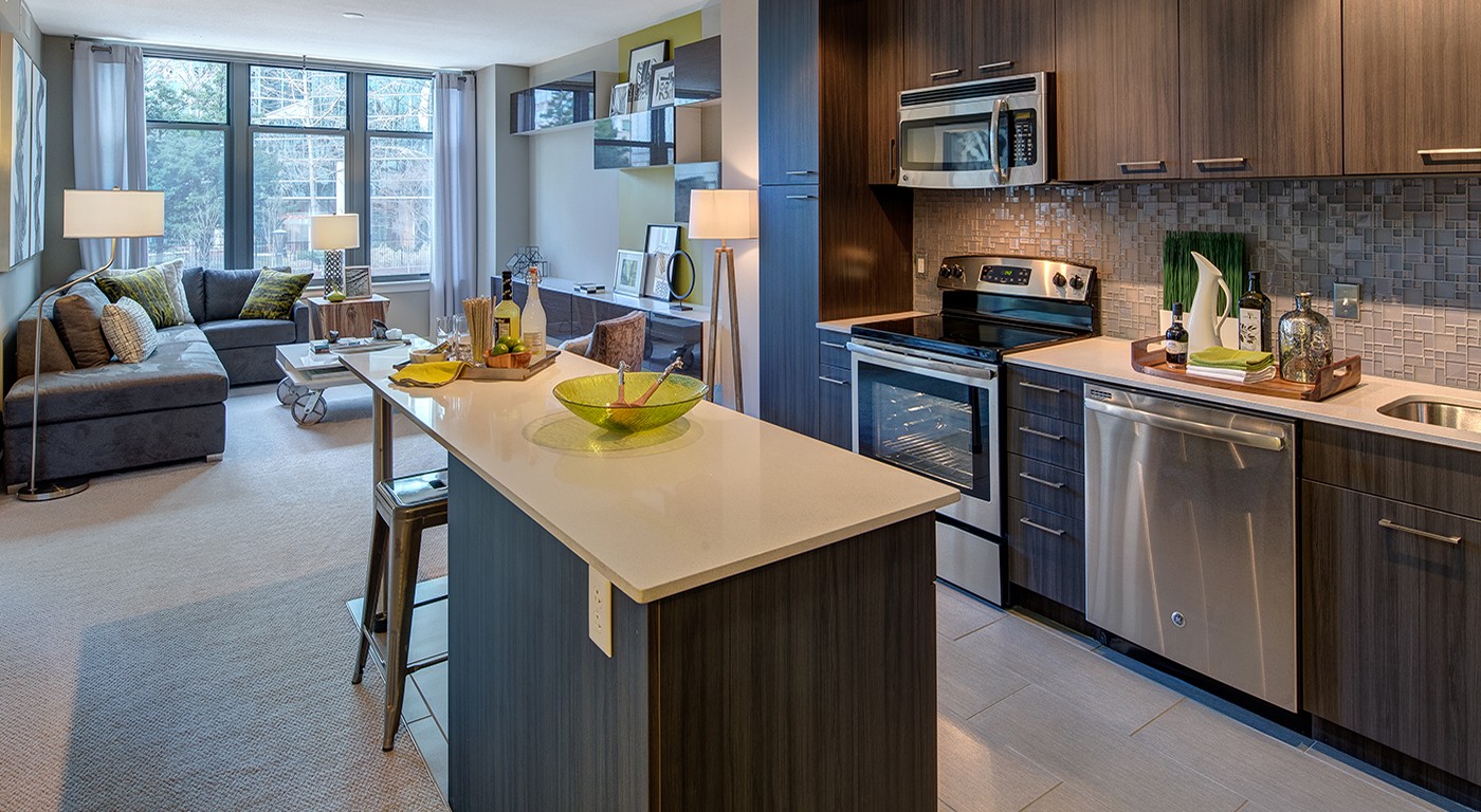 tellus kitchen with quartz countertops, stainless steel appliances, island, and view of the living area - jefferson apartment group