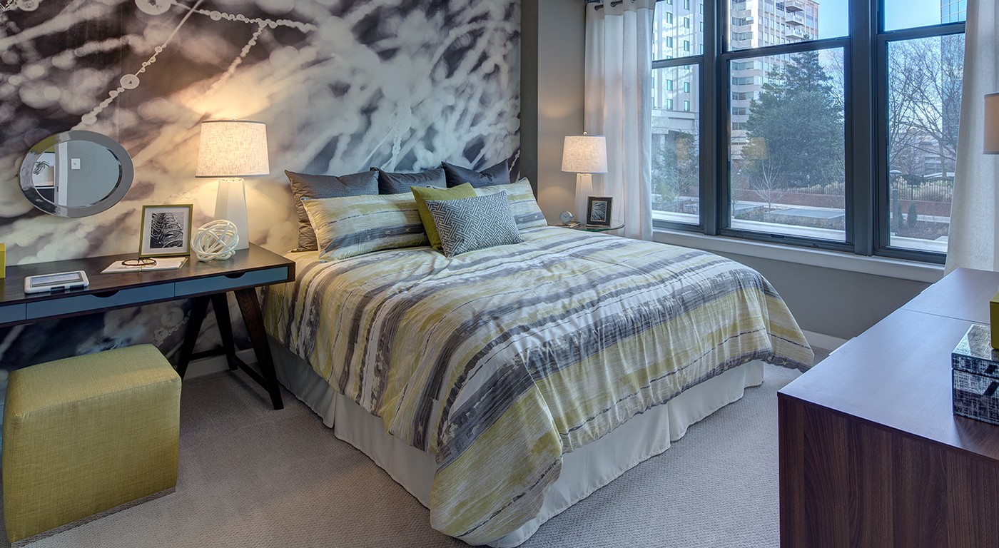 tellus bedroom with bed, desk, dresser, modern wall art, large windows and decorative lamps - jefferson apartment group