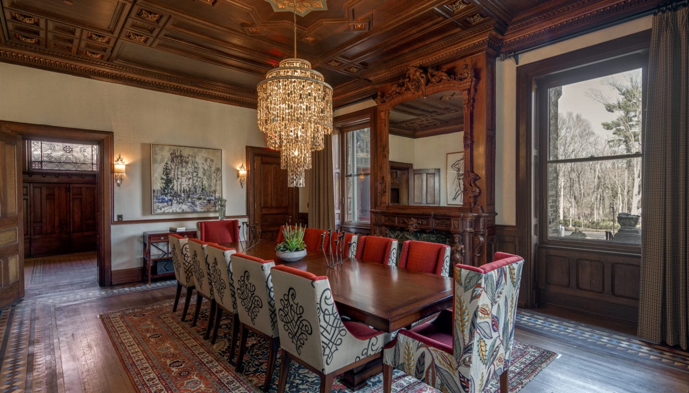 maybrook mansion dining area with large table, twelve chairs, chandelier, artwork, intricate mirror and large windows - jefferson apartment group
