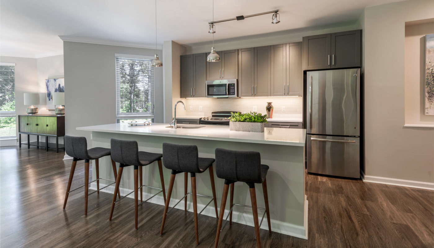 maybrook dining area with breakfast bar, four barstools, stainless steel appliances, quartz countertops and sleek plank flooring - jefferson apartment group