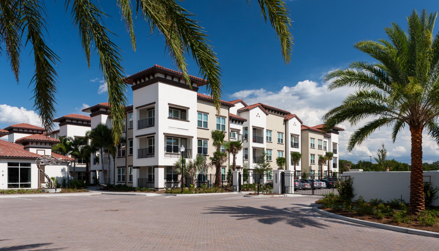 westshore exterior showing three story building with balconies, palm trees, and parking area - jefferson apartment group