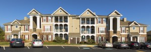 somerset park exterior showing three story building with stone accents, lush green lawn and large parking lot - jefferson apartment group