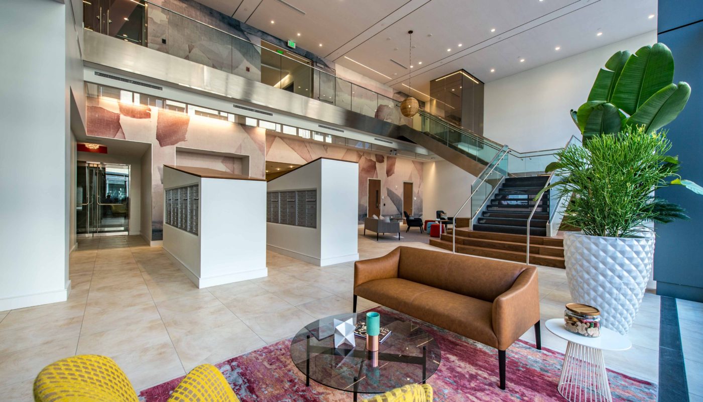 j malden center lobby with social seating, colorful rug, large indoor greenery, grand staircase and the mail center in the background - jefferson apartment group