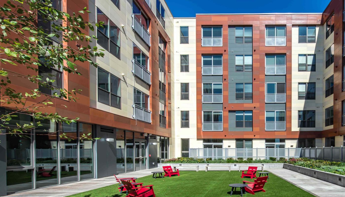 j malden center outdoor courtyard with lush lawn, bench seating and red Adirondack chairs - jefferson apartment group