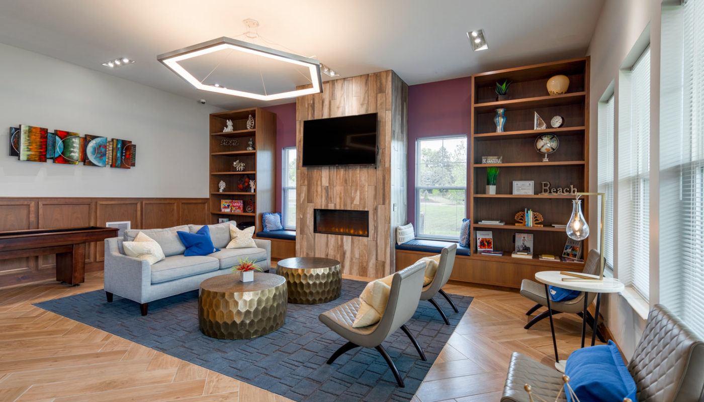 emblem resident lounge with social seating, shuffleboard table, fireplace, book shelves, modern lighting and flat screen tv - jefferson apartment group