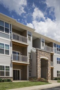 three story building with stone accents, balconies and lush green lawn - jefferson apartment group