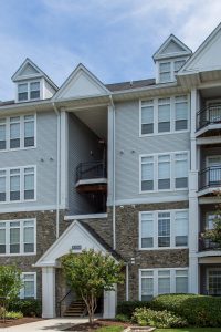 arbors at broadlands exterior showing a four story building with balconies, trees, lush landscaping and stone accents - jefferson apartment group