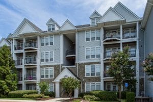 arbors at broadlands exterior showing a four story building with balconies, trees, lush landscaping and stone accents - jefferson apartment group