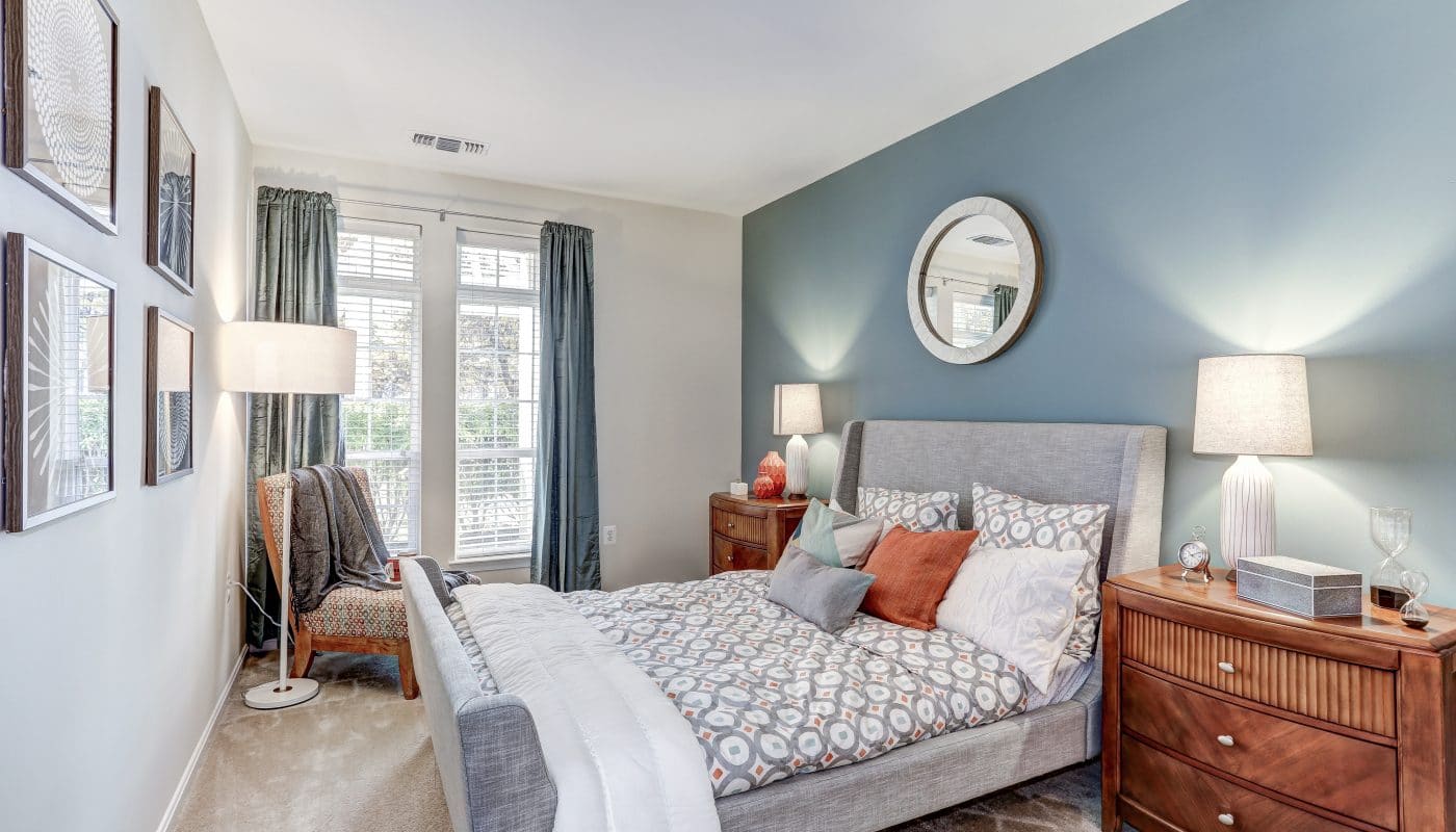 arbors at broadlands bedroom with bed, night stand, large windows and modern artwork - jefferson apartment group
