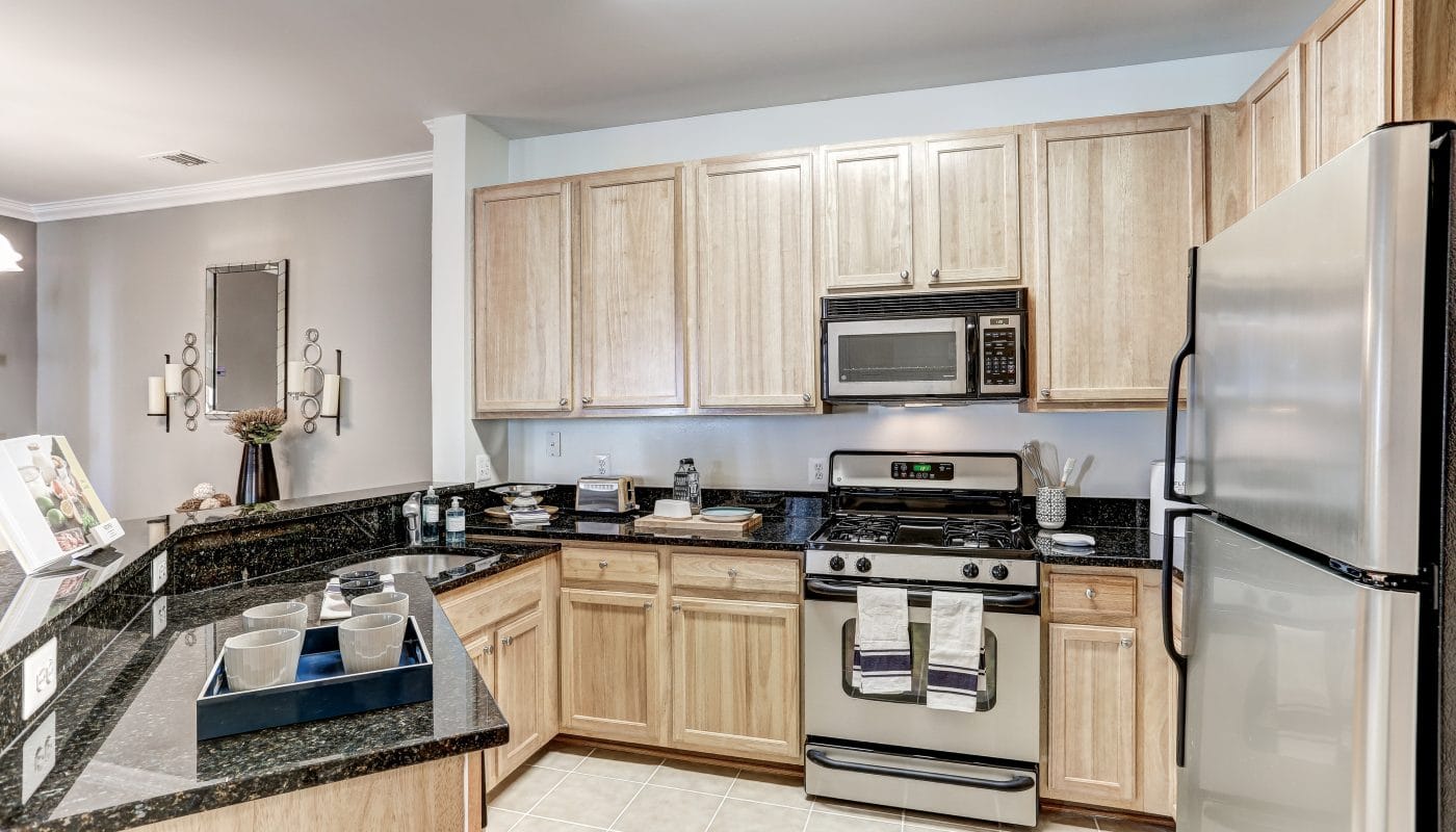 arbors at broadlands kitchen with stainless steel appliances, granite countertops, tile flooring and view of living area - jefferson apartment group