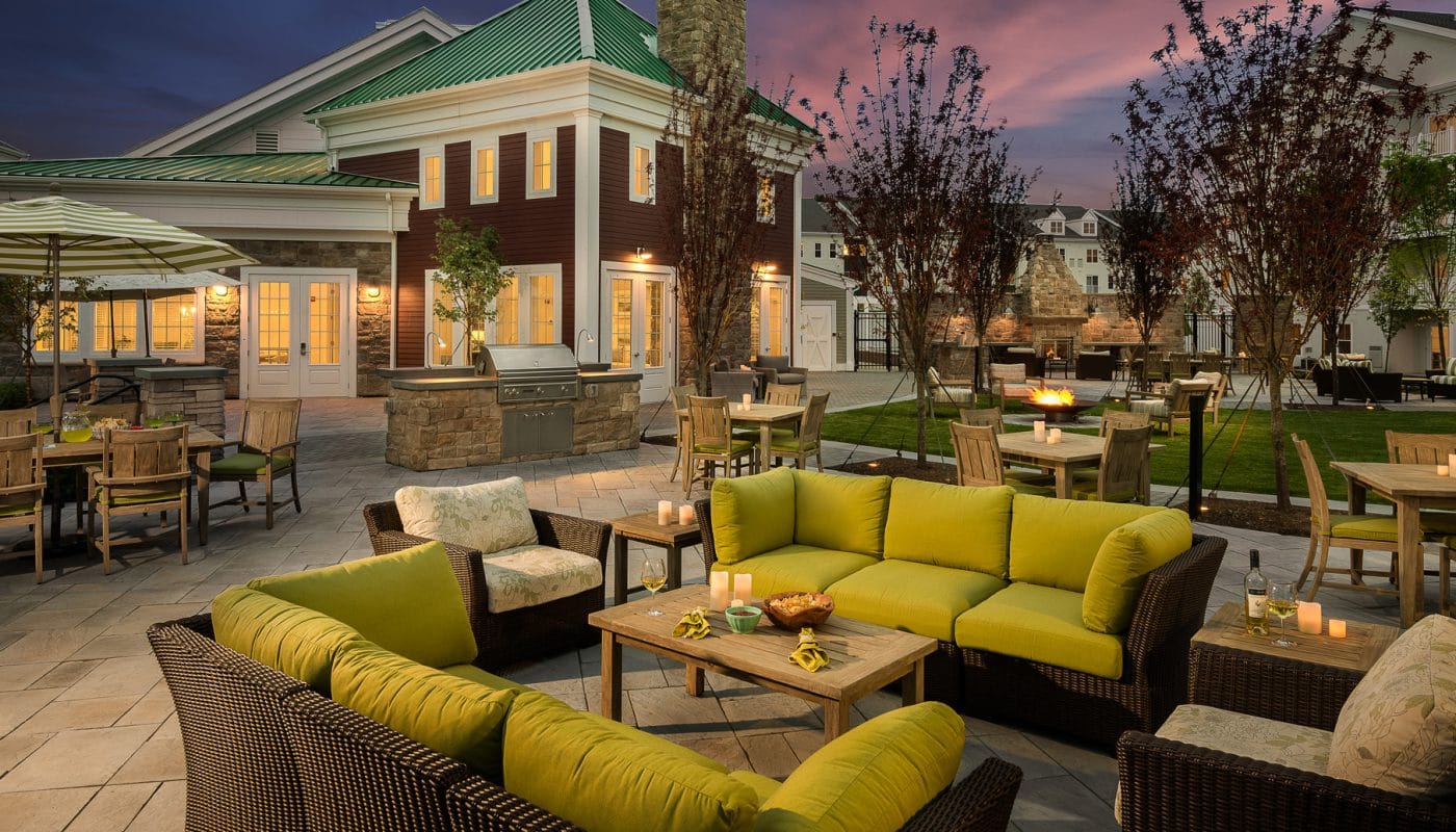 one upland outdoor living area with grilling stations, dining tables, social seating and view of apartment building in the background - jefferson apartment group