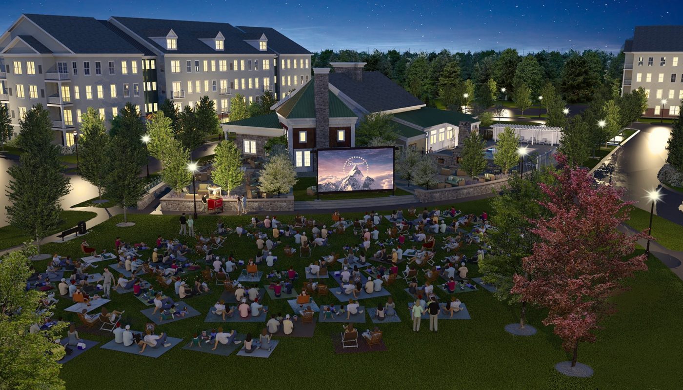 one upland outdoor movie night with large screen and many people watching on blankets and patio chairs. view of apartment building in the background - jefferson apartment group