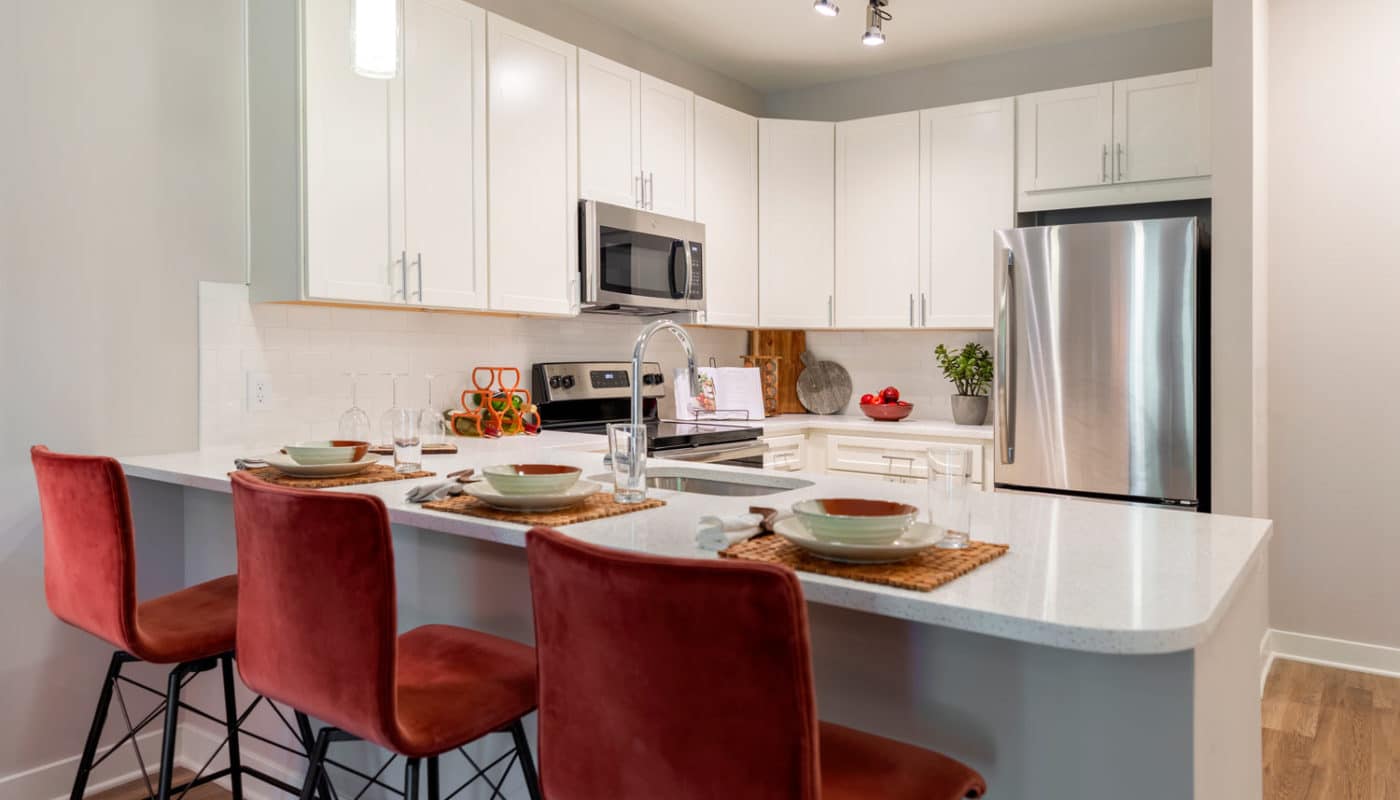 jefferson mount laurel kitchen with breakfast bar, bar stools, place settings, stainless steel appliances, quartz countertops and white cabinetry - jefferson apartment group