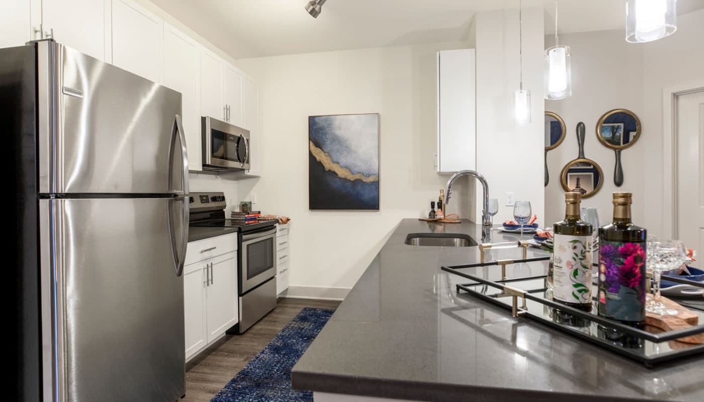 j creekside at exton luxury apartments kitchen with stainless steel appliances, quartz countertops, plank flooring, and modern artwork - jefferson apartment group