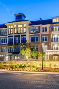 exterior of 4 story apartment building with nice landscaping at dusk