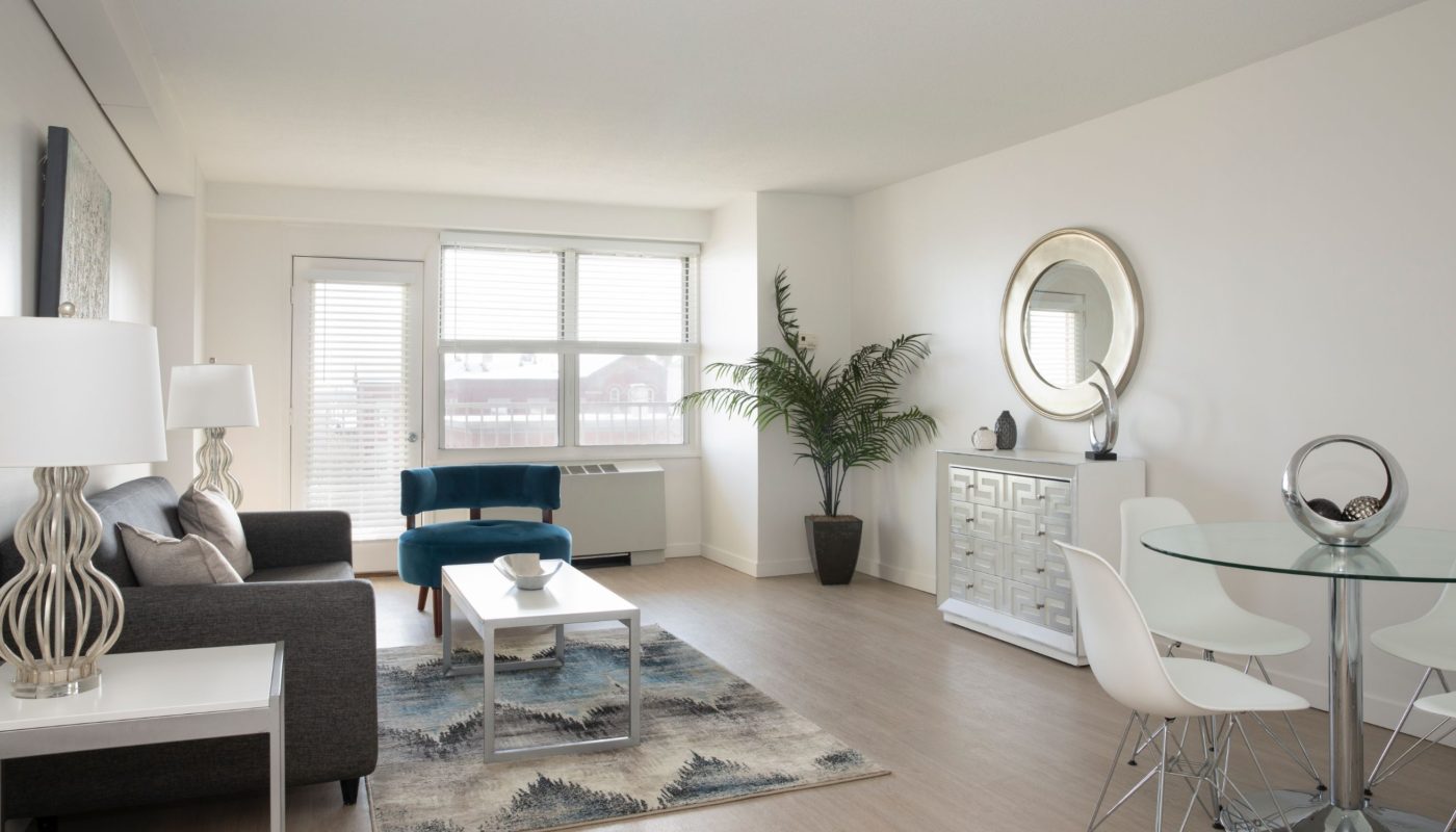 living area with sofa, coffee table, end tables, large windows and dining area a boston apartment