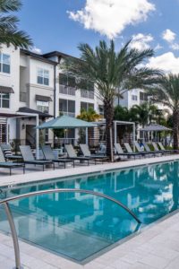 exterior of 3 story apartment building with screened in balconies and view of pool at jefferson lake howell luxury apartments in Casselberry