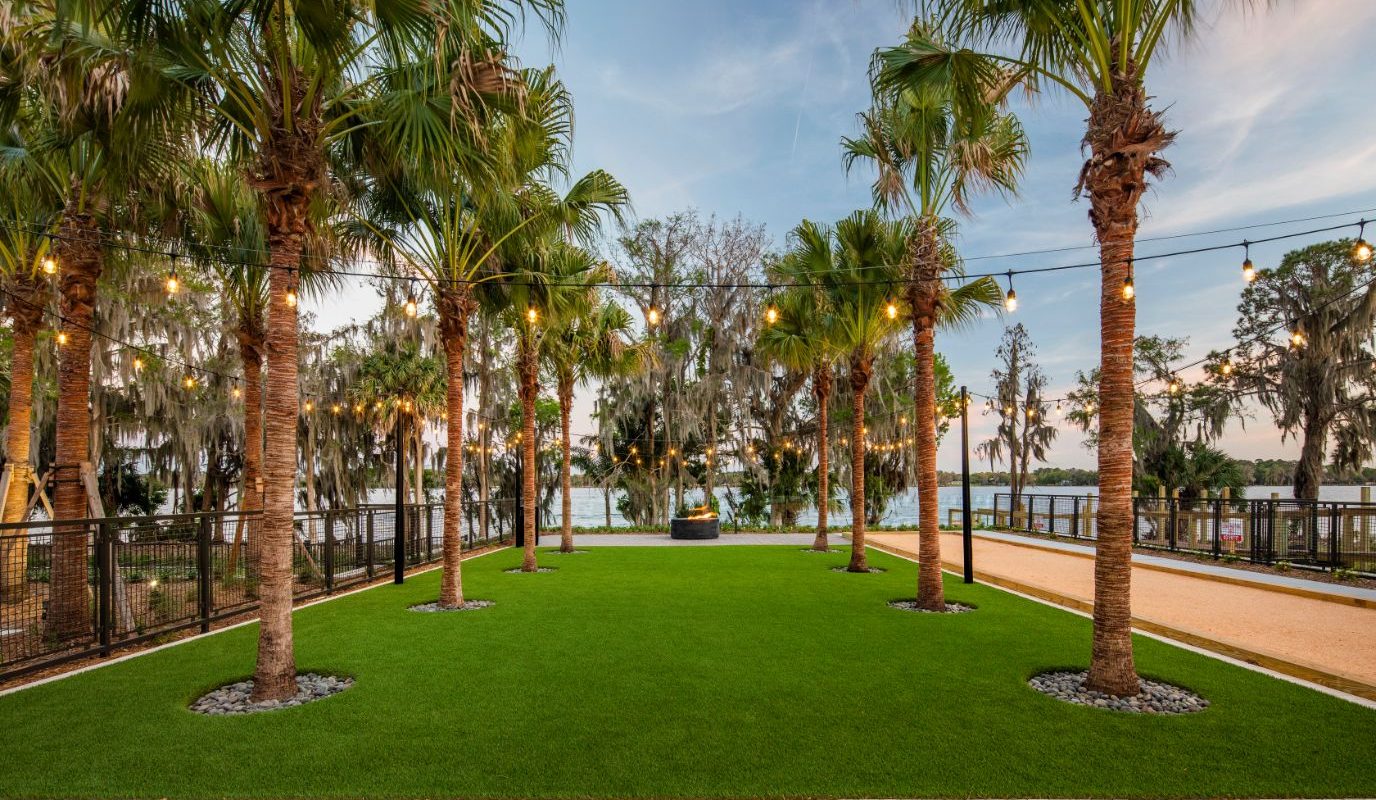 courtyard with palm trees, bocce ball court, fire pit, and view of lake in casselberry fl