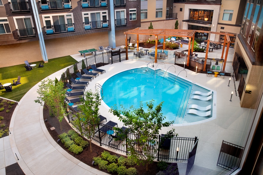 pool with lounge chairs, lush landscaping, pergola, social seating and grills at scout on the circle fairfax luxury apartments