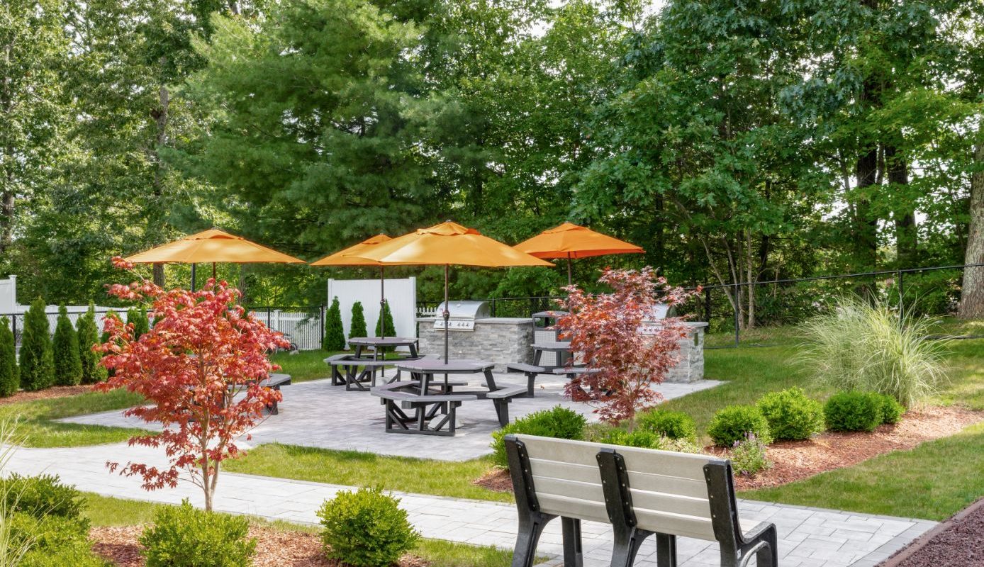 picnic area with tables, chairs, umbrellas and grilling stations at j highlands at hudson apartments