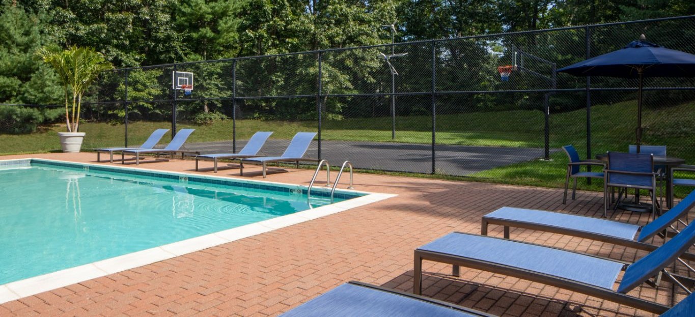 swimming pool, chaise lounge chairs and view of sports court at j highlands at hudson apartments