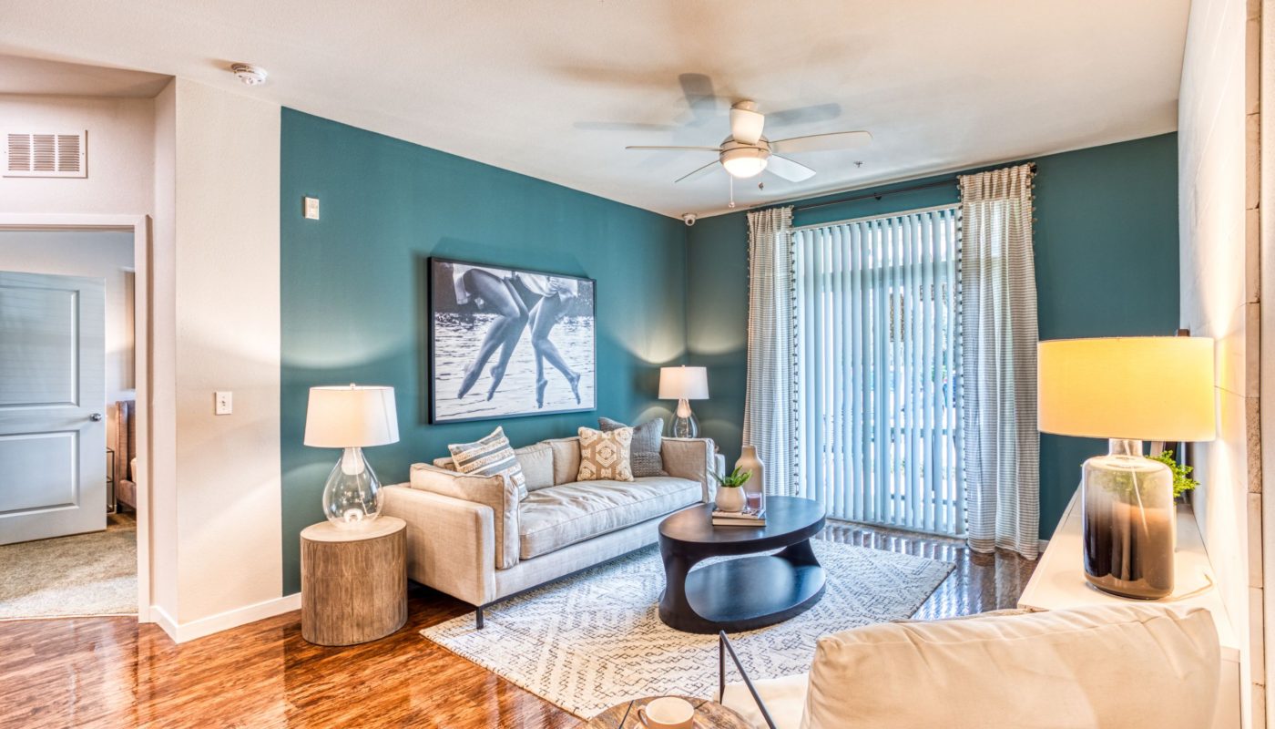 living area with couch, coffee table, end table, decorative lighting, large window, ceiling fan and modern artwork at sea isle luxury apartments