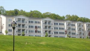 exterior of 4 story apartment building, wooded area and lush lawn at j highlands at hudson luxury ma apartment exterior
