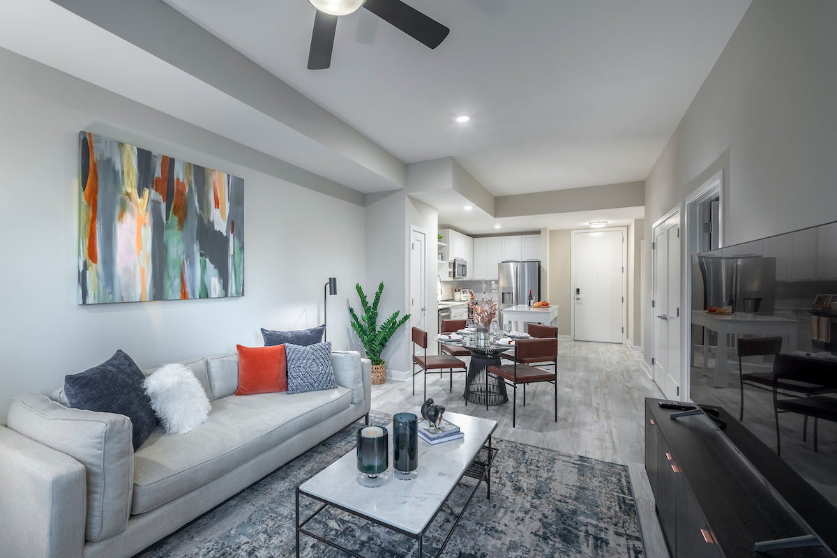 living area with social seating, coffee table, tv, modern artwork and floor to ceiling windows with at Aventon crown luxury Gaithersburg apartments
