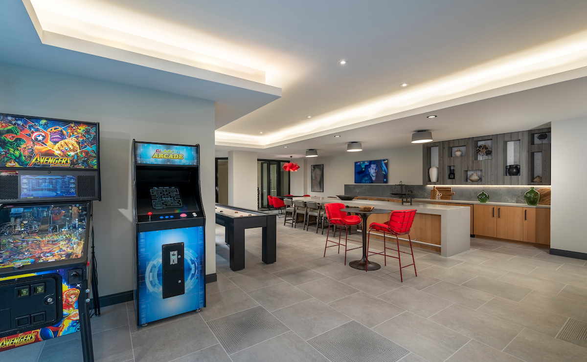 game room with large flat screen, shuffleboard, arcade games, bar seating and modern lighting at Aventon crown luxury Gaithersburg apartments