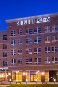 5 story building exterior at night - South Alex Apartments