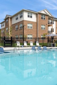 pool with chaises and 3 story building exterior - brandywine green apartments