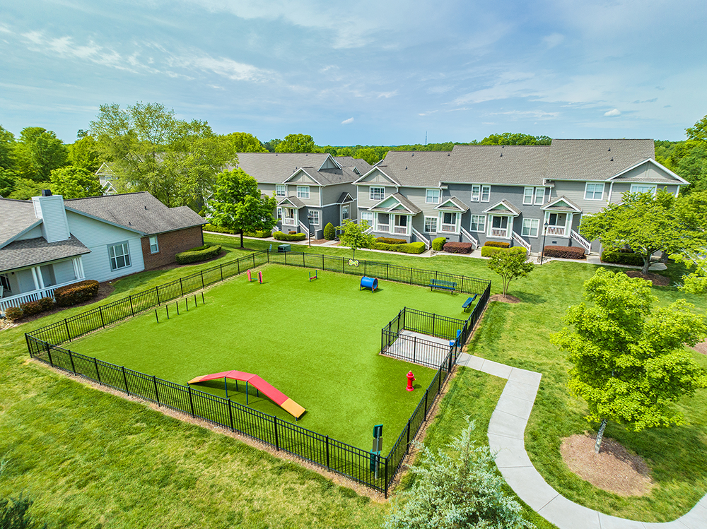 Large dog park with agility equipment next to townhomes at J501 Estates